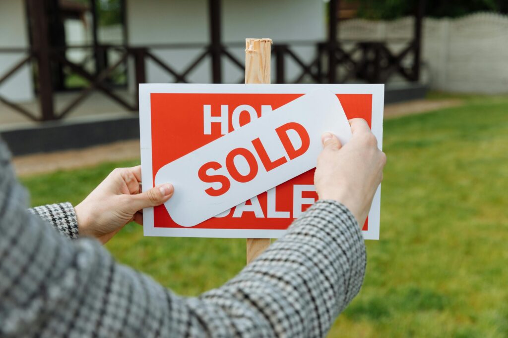 a realtor posting a sold sticker on a sign