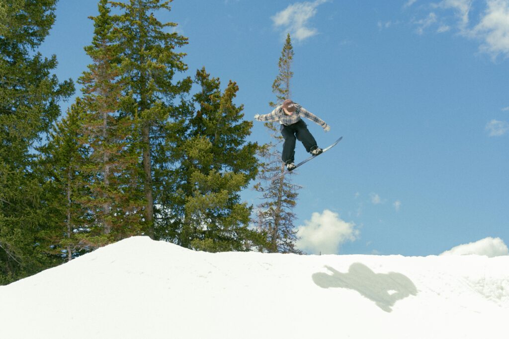 snowboarder mid jump at a huge pile of snow