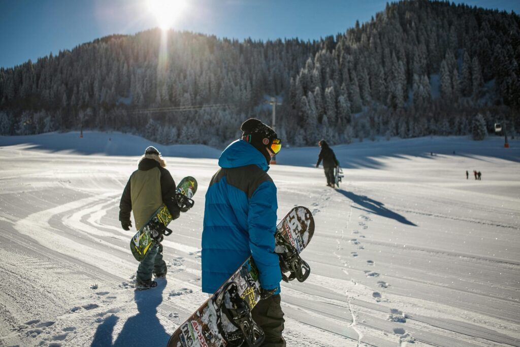 a person wearing blue winter jacket carrying a snowboard under sunny sky