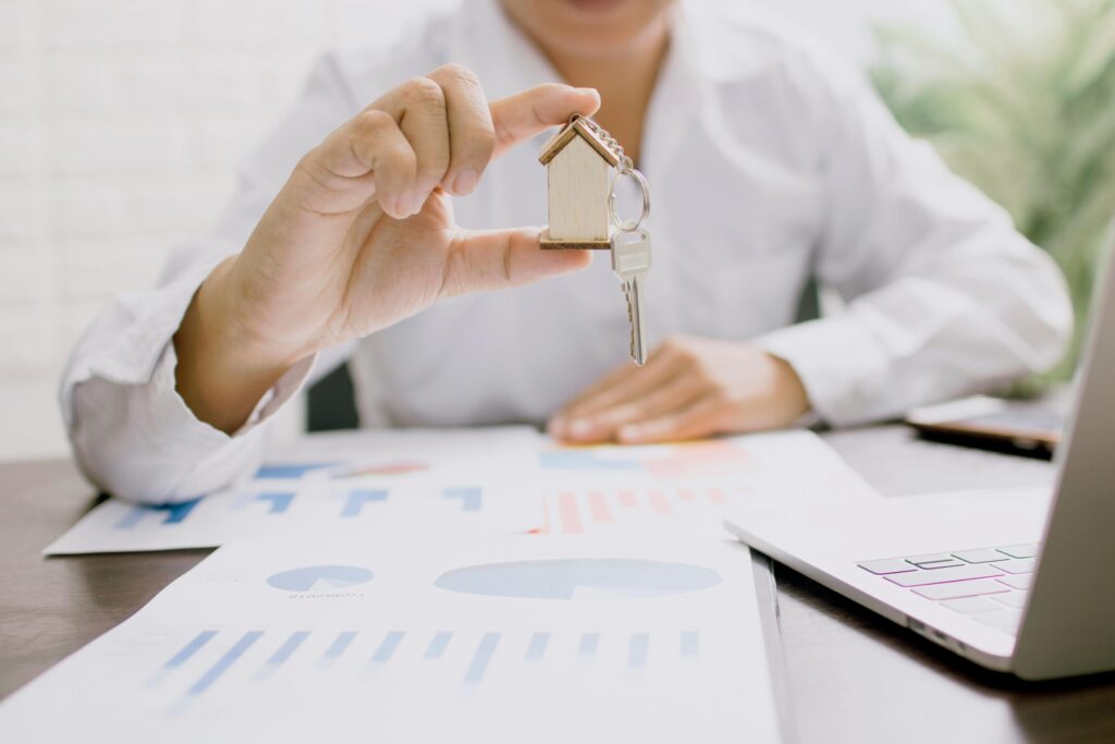 a person holding a key with a house keychain