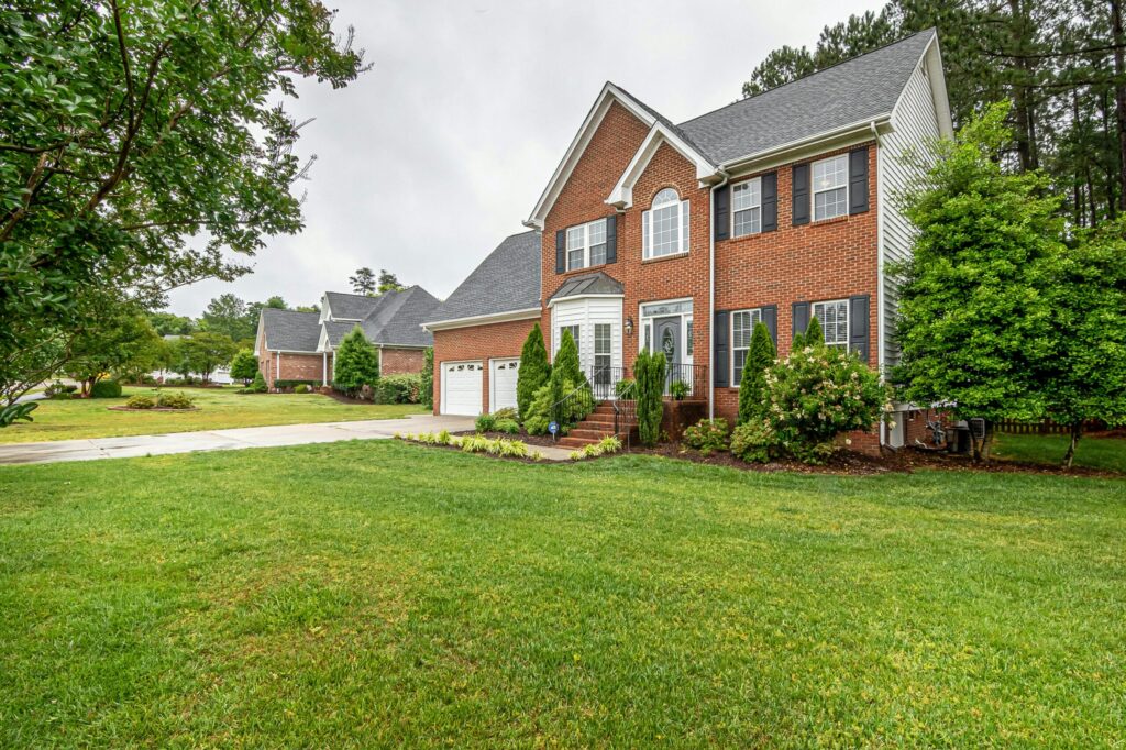a two story brick house with attached garage and well maintained lawn